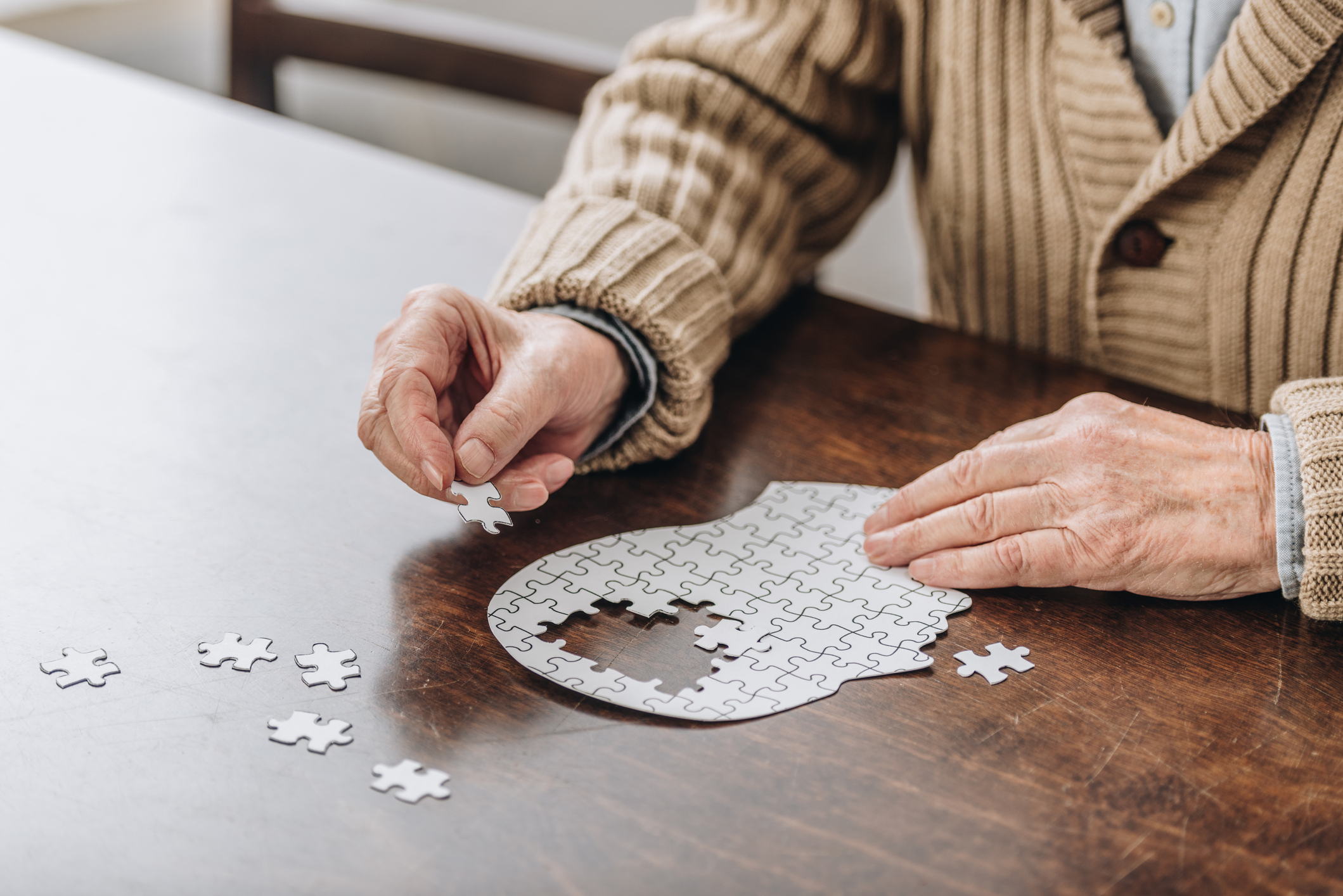 cropped view of senior man playing with puzzles Volunteer with Respite Care Atlanta